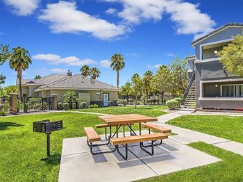 A picnic table in a backyard with a grill